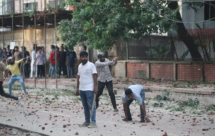 আন্দোলনকারী শিক্ষার্থীদের লক্ষ্য করে আগ্নেয়াস্ত্র তাক করে আছেন এক তরুণ। আজ সোমবার বিকেলে শহীদুল্লাহ হল এলাকায়ছবি: সাজিদ হোসেন